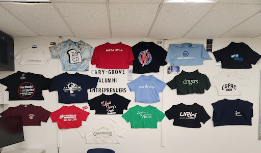 Shirts of companies Theresa's students founded displayed on the wall in her classroom.